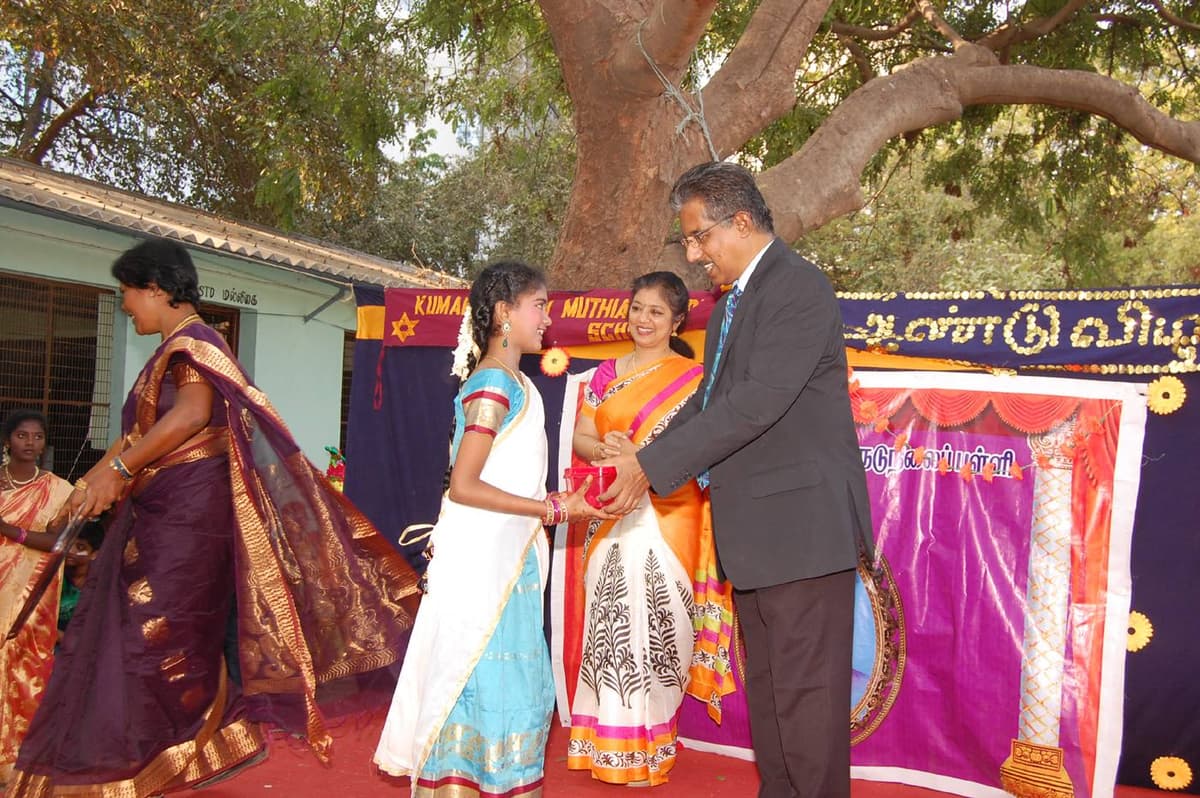 Dr. Sundararaman distributing prize to student on stage with Dr. Meena Muthiah