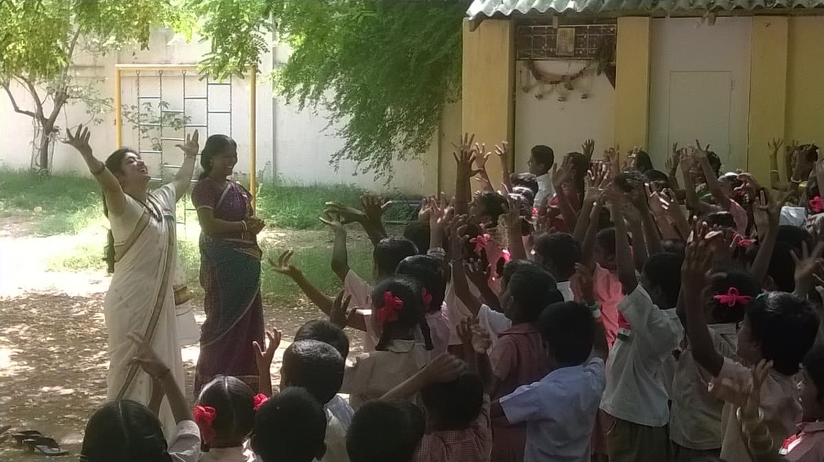 Children enthusiastically participating in Independence Day activity with hands raised