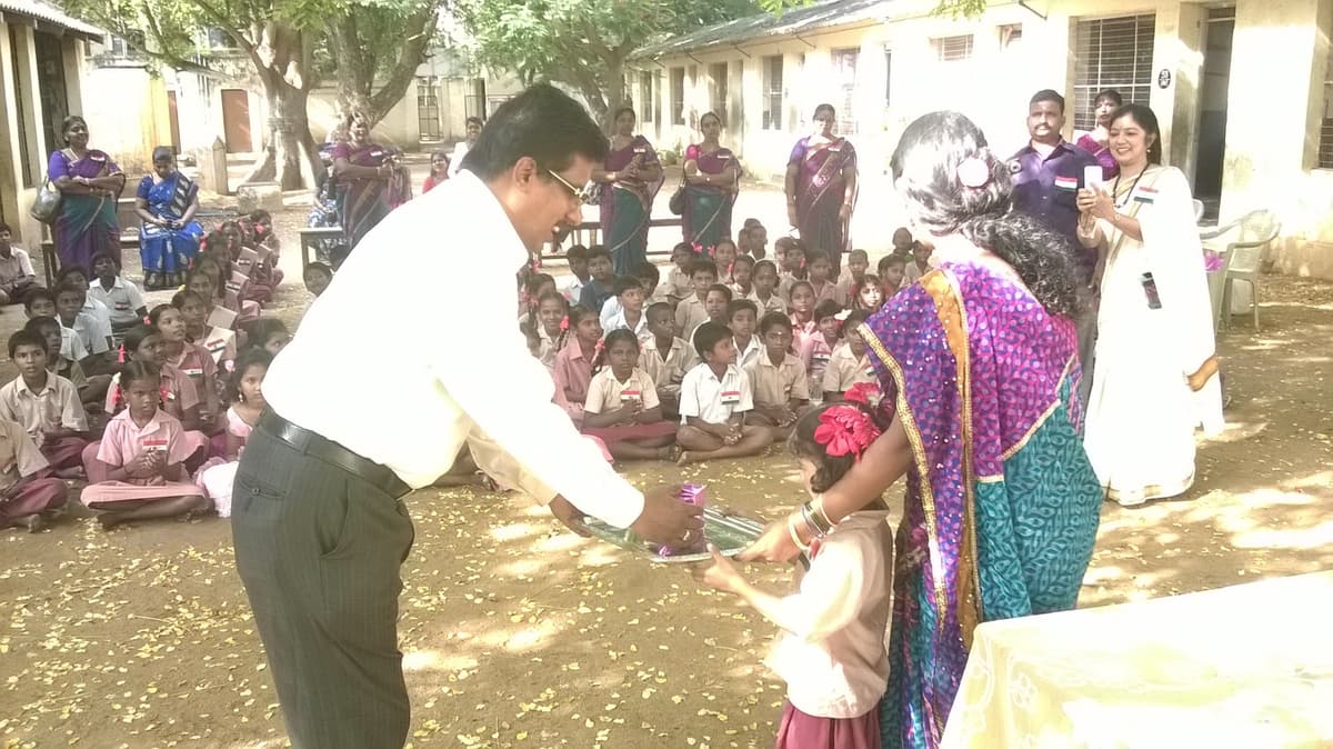 Dr. Sundararaman distributing prizes to a student with teachers watching